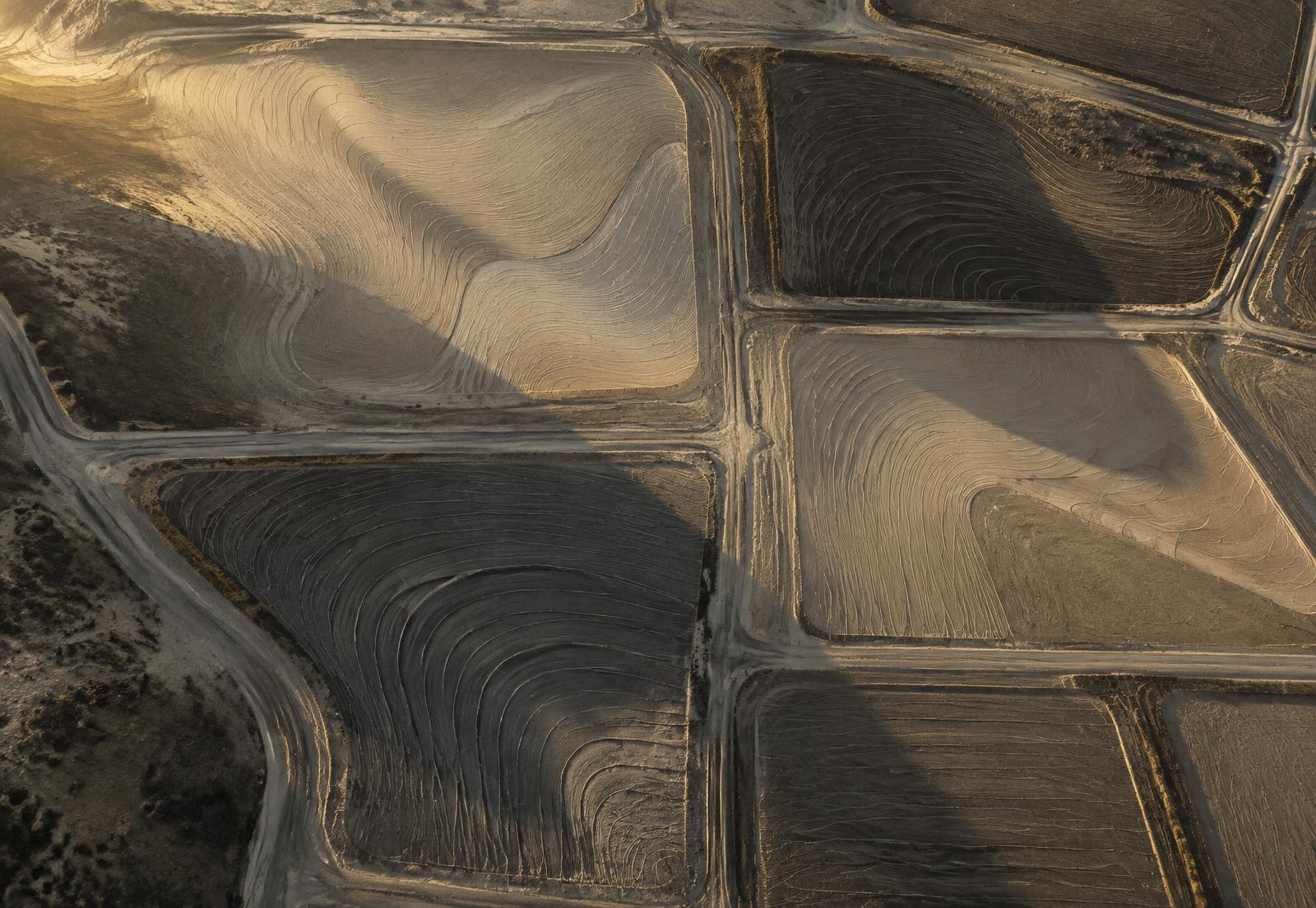 Aerial view of earthen land parcels with contour patterns in low golden light